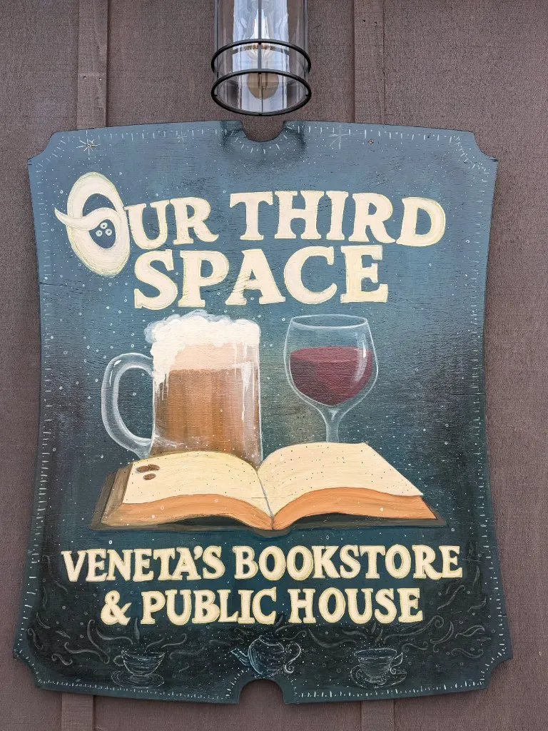 Hand-painted wooden exterior sign for Our Third Space, Veneta’s bookstore and public house.